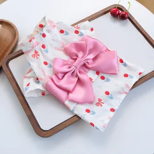 Detail van de zomerse yukata voor honden met bloemenprint en grote roze satijnen strik