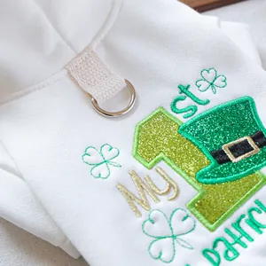 Detail of St. Patrick's Day embroidery and metal D-ring on white pet sweatshirt