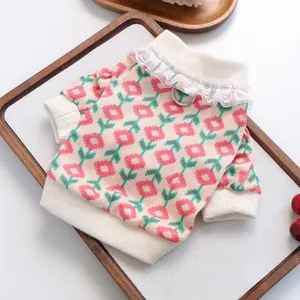 Close-up of knit pet sweater with floral pattern, lace collar and metal D-ring for leash