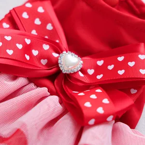 Macro shot of a red ribbon bow with heart prints and pearl center on the pet dress