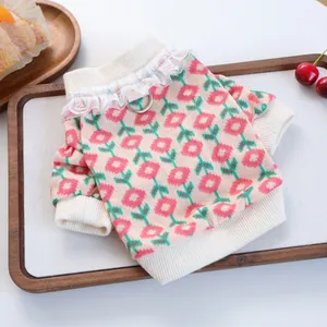 Pink and white knitted pet sweater with red floral patterns and lace collar detail