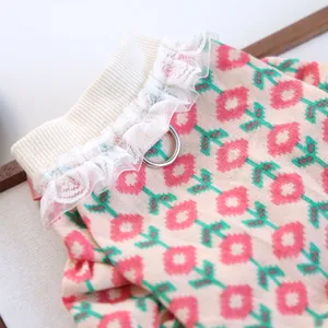 Detailed view of apricot pet knitwear with pink floral patterns and white lace trim