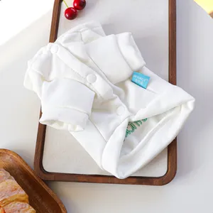 Close-up of a white knit pet cardigan with buttons and brand label on a tray