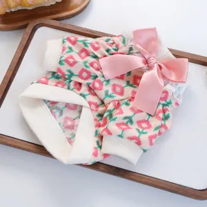 Macro detail of pet knitwear with floral patterns, pink satin bow and white lace trim