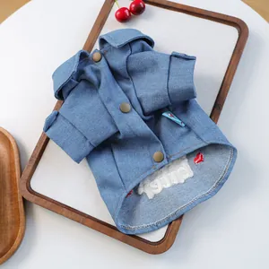 Detail view of denim pet jacket featuring vintage brass buttons and white embroidery