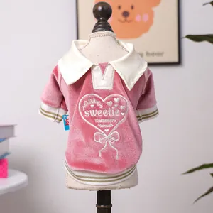 Close-up of pink velvet pet polo shirt featuring white heart embroidery and gold trim