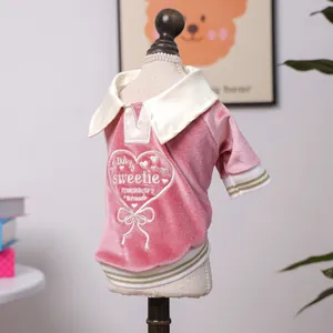 Close-up of pink velvet pet polo shirt with heart embroidery and gold striped cuffs