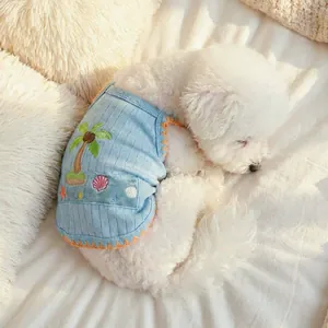 Puppy in blue striped summer vest with coconut tree embroidery on soft white cushion