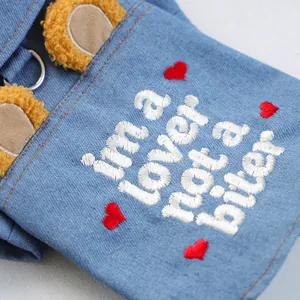 Detail of pet denim vest featuring plush bear ears, red hearts, and a metal D-ring