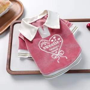 Detail of pink velvet pet polo shirt with heart embroidery and gold striped cuffs