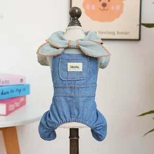 Detail of dog denim overalls featuring a light green bow collar and Hello patch