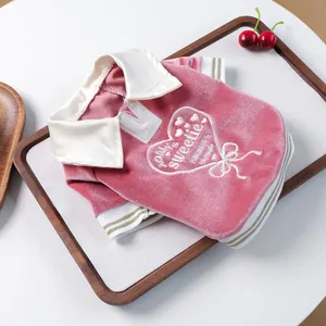 Detail of pink velvet pet polo shirt featuring heart embroidery and gold striped cuffs