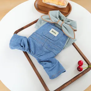 Detailed view of green pet shirt with bow tie and blue denim overalls on a wooden tray