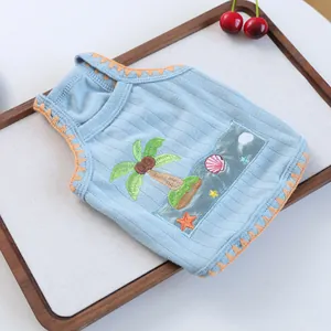 Close-up of light blue pet vest with coconut tree embroidery and orange zigzag edges