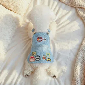 Lichtblauwe denim hondenjurk met vintage patches op een wit pluche tapijtje