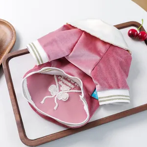 Detail of pink velvet pet polo shirt with white bow embroidery and ribbed cuffs