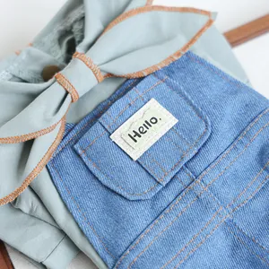 Detail of pet overalls with denim pocket, hello embroidery, and large bow decoration
