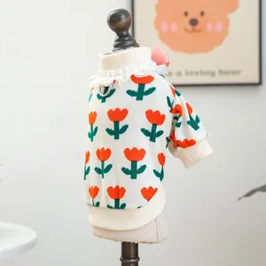 Detail of pet knit sweater with orange tulip patterns, lace collar, and pink bow accent