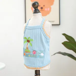 Detail of blue knit dog vest featuring tropical embroidery and orange scalloped trim