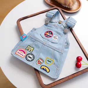 Detail van een blauwe denim huisdierjurk met vintage geborduurde patches en metalen gespen