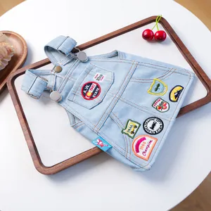 Detail van een kleine denim overall voor huisdieren met vintage borduursels en metalen gespen