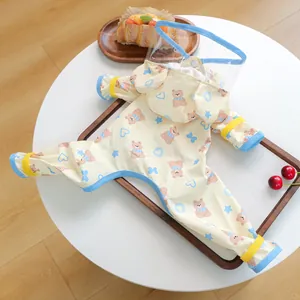 Detail of waterproof dog raincoat with bear print, transparent hood, and adjustable straps