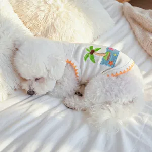 Detail of white dog vest with tropical palm tree embroidery and orange serrated trim