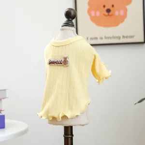 Nahaufnahme von gelbem Strickpullover für Haustiere mit Rüschen und Bären-Stickerei