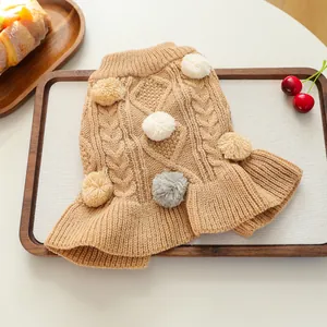 Detail of cable knit pet sweater with decorative pom-poms and ruffled hemline