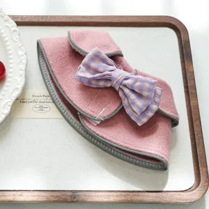 Dettaglio dello scialle in lana rosa per animali con fiocco a quadri viola e bordo