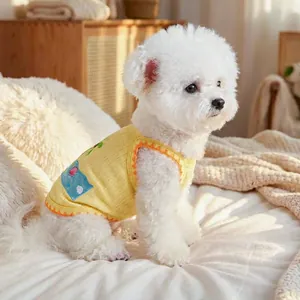 Close-up of yellow pet vest with ocean shell pocket on a white Bichon dog