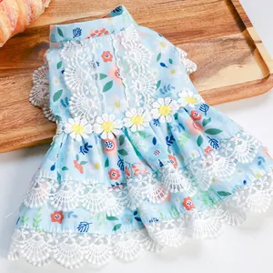 Detailed view of floral pet dress with lace trim and yellow daisy accents on wooden tray