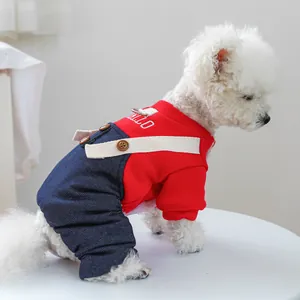 Detail of red knit sweater and denim pet overalls with HELLO embroidery on a Bichon