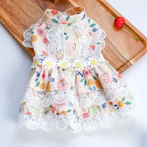 Detail of floral pet dress with white lace trim and yellow flower on wooden tray