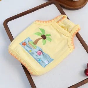 Detail of pet vest showing coconut tree embroidery and orange wavy knit edges on yellow fabric