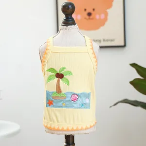 Detail of pet knit vest with palm tree embroidery and orange wavy hem on yellow fabric