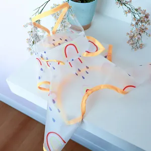 Close-up of transparent dog raincoat with colorful rainbow prints and yellow trim detailing