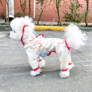Detail of waterproof pet raincoat featuring rainbow prints and red trim on a white dog