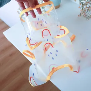 Close-up of transparent pet raincoat with rainbow print and yellow piped edges