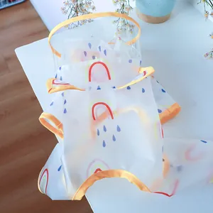 Close-up of waterproof transparent PVC dog raincoat with rainbow and blue raindrop patterns