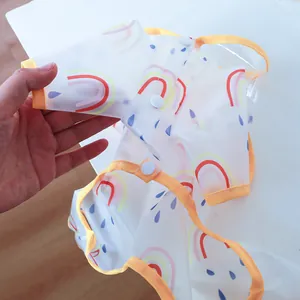 Detail of translucent waterproof pet raincoat with rainbow print and orange trim