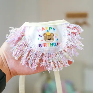 Detailed embroidery of a birthday bear and tassels on a white pet bandana bib
