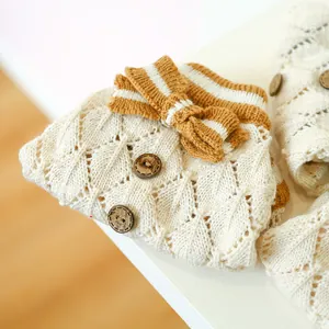 Detail of hollow diamond knit pattern with wooden buttons and striped bow on pet sweater