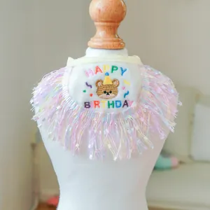 Detail view of white plush pet birthday bib with Happy Birthday embroidery and colorful tassels