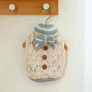 Close-up of knit pet sweater with hollow texture, wooden buttons and blue bow details