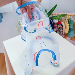 Detail of waterproof pet raincoat featuring rainbow patterns and a transparent hood