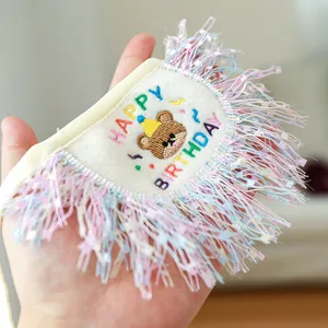 Macro detail of pet birthday bib with teddy bear embroidery and colorful fringe