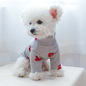 Detail of grey knitted dog sweater with red hearts and soft ribbed texture on a bichon