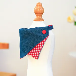 Detailed view of reversible denim and red plaid pet bandana with red button detail