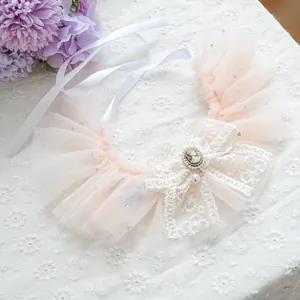 Detail of peach pink lace pet bib featuring a vintage cameo and teardrop pearl pendant